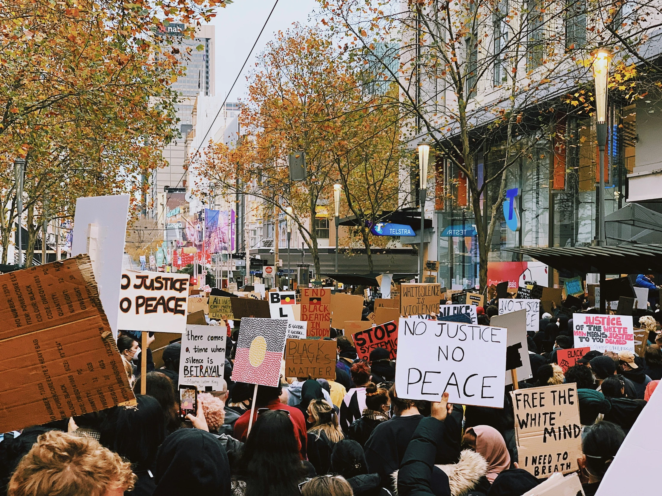 people march in protest with signs reading justice no race