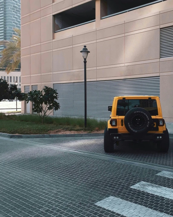 a yellow jeep parked by the side of a building