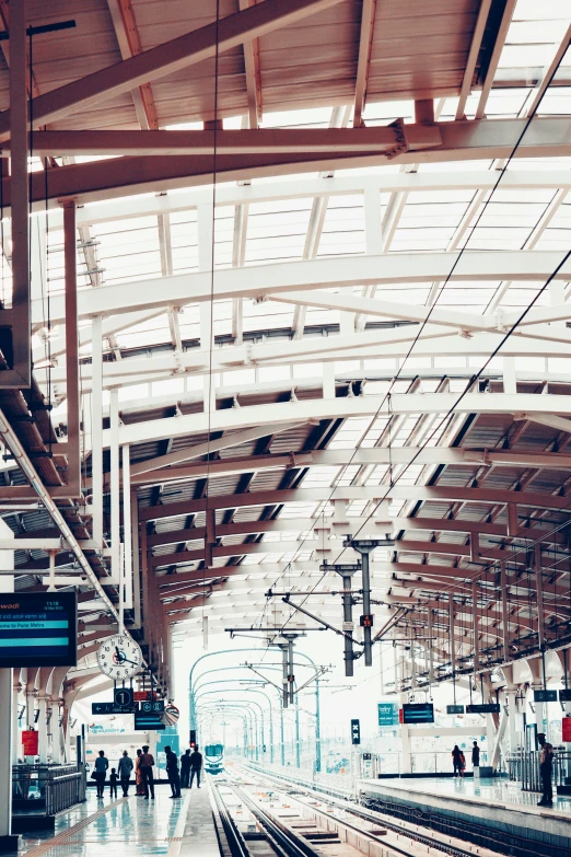 a train station with overhead train tracks and people walking around