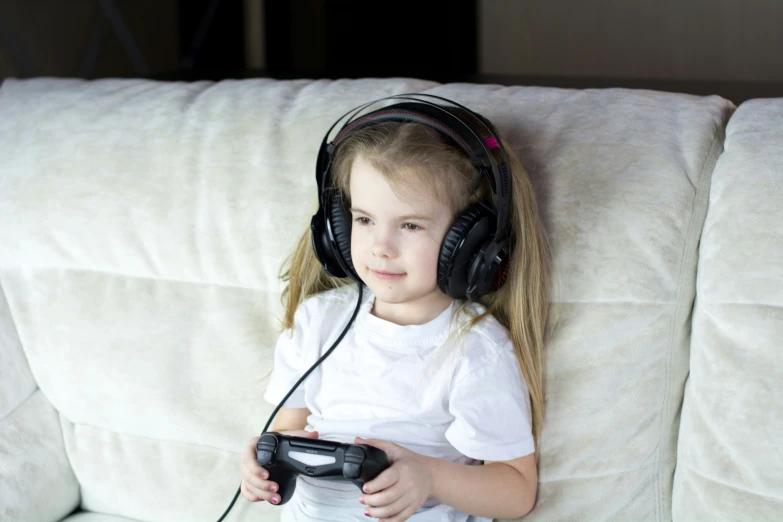 little girl with headphones on playing a video game
