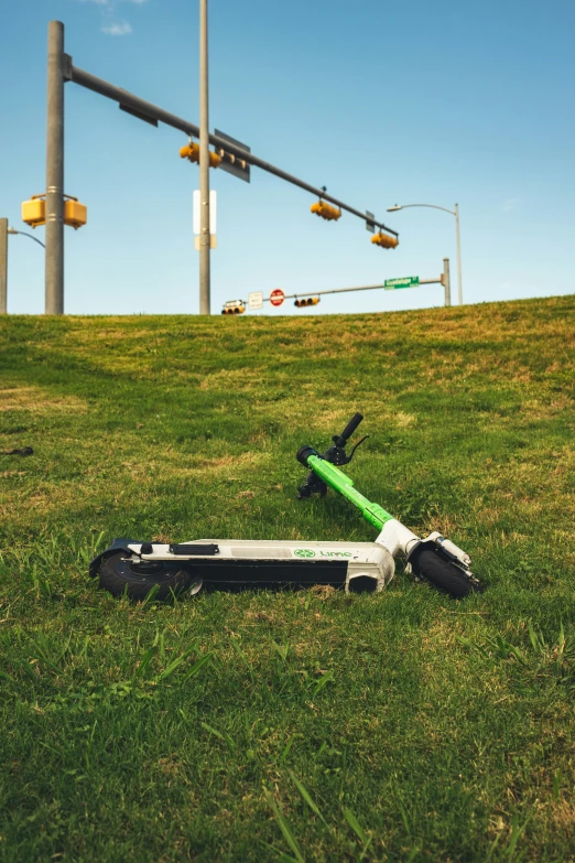 a scooter sitting in the grass near a traffic light