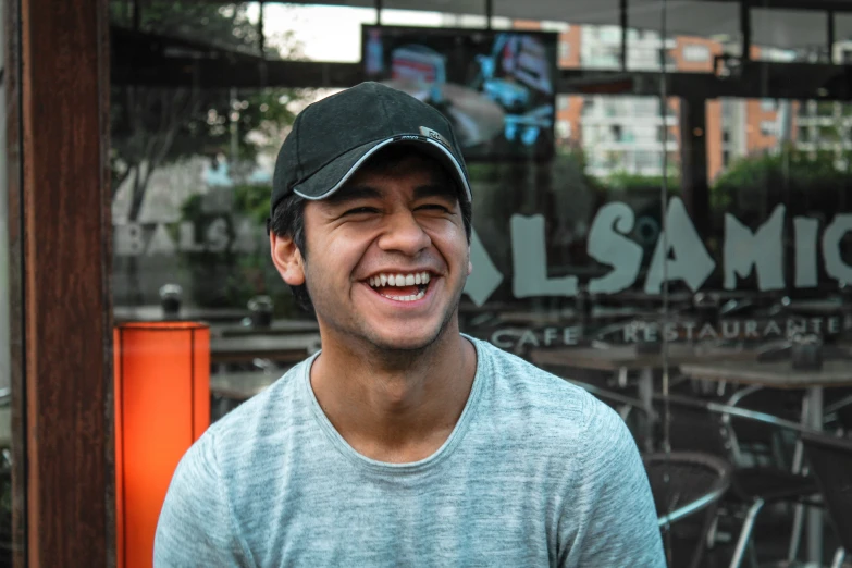 there is a smiling young man in front of a cafe