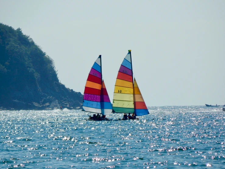 a rainbow sailboat on the water with another boat nearby