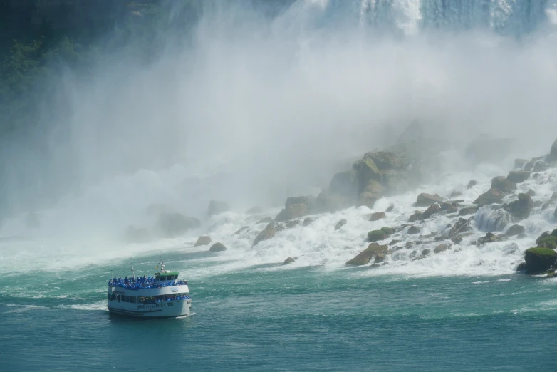 a large boat is traveling in the water near a large waterfall