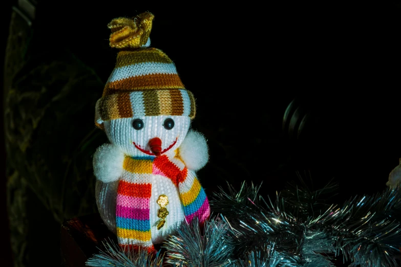 a colorful stuffed snowman in a christmas hat with a gold ball