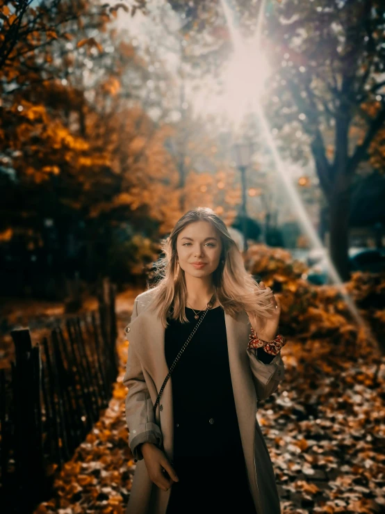 woman standing in leaves in front of trees