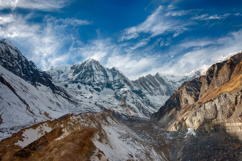 snowy mountains against a partly cloudy sky with clouds