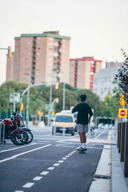 man on skateboard with bag walking towards building near street