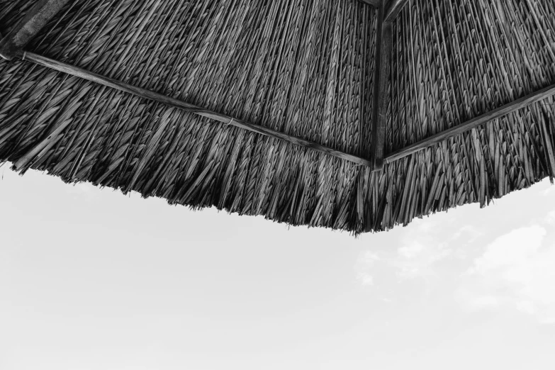 a thatch umbrella with clouds in the background