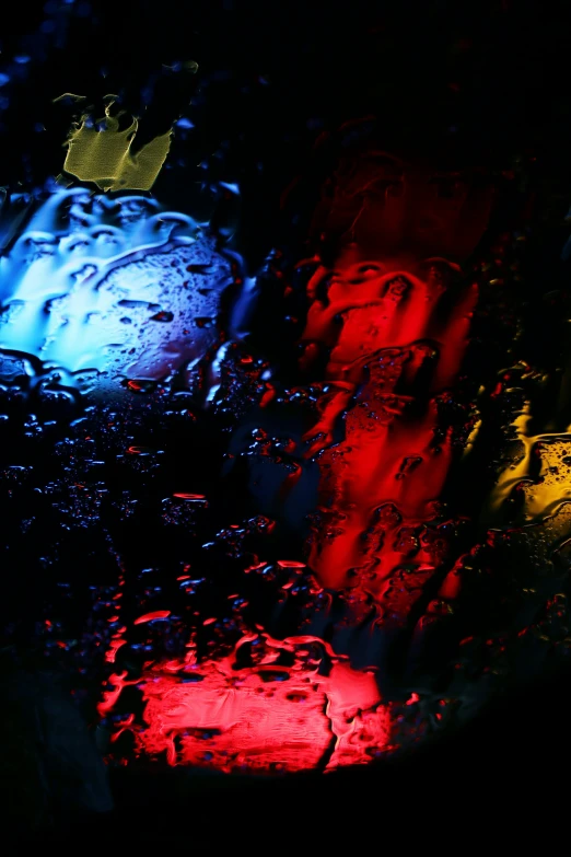 rain covered windshields with a colorful, brightly lit streetlight