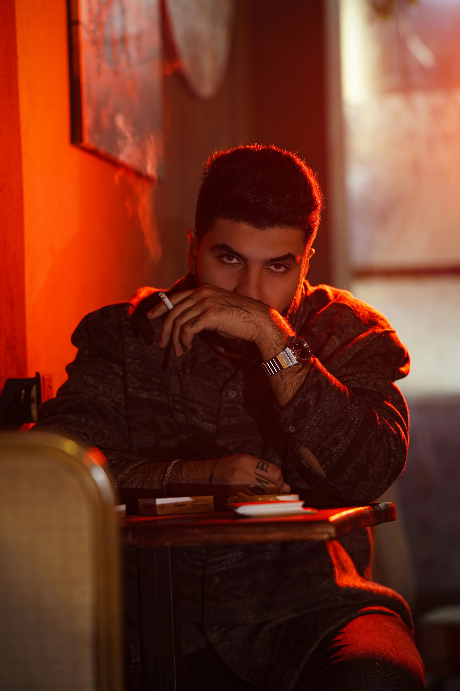 a young man in a dimly lit room holding his hand on his head