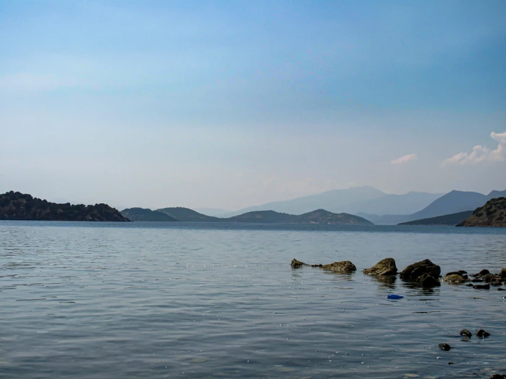 a lake with some rocks in it and hills near by