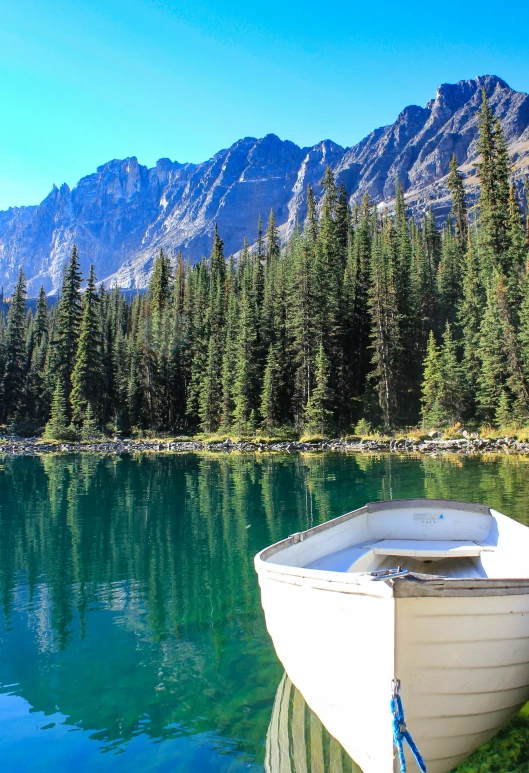 a small boat sits docked near a mountain lake