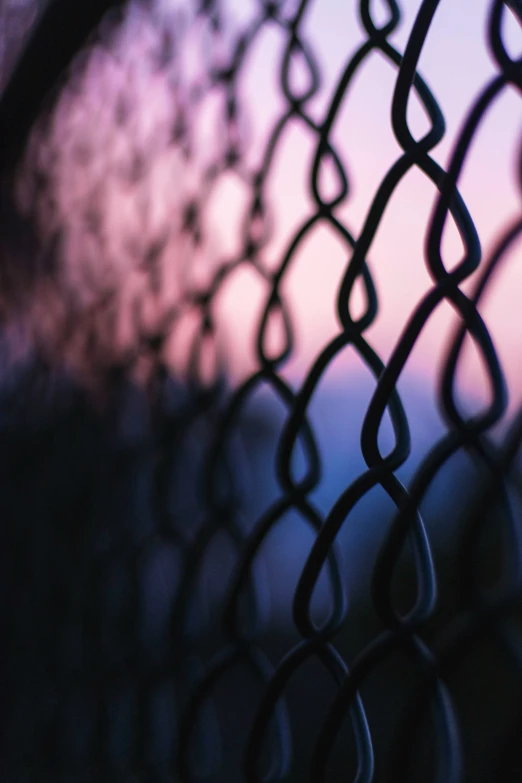 the back end of a chain link fence, with some light in the background