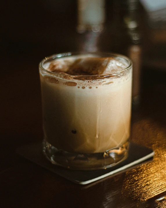 a drink sitting on a bar next to a metal coaster