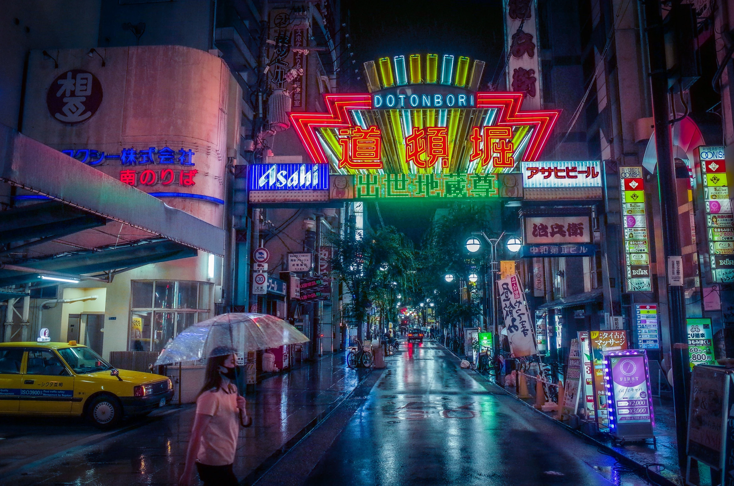 city street with lit neon sign and person walking under an umbrella