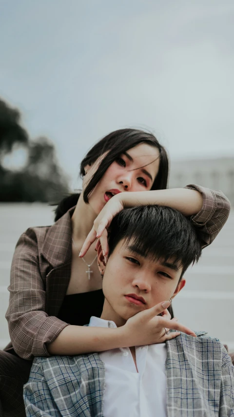 a woman leans on the back of a boy with his arm around him