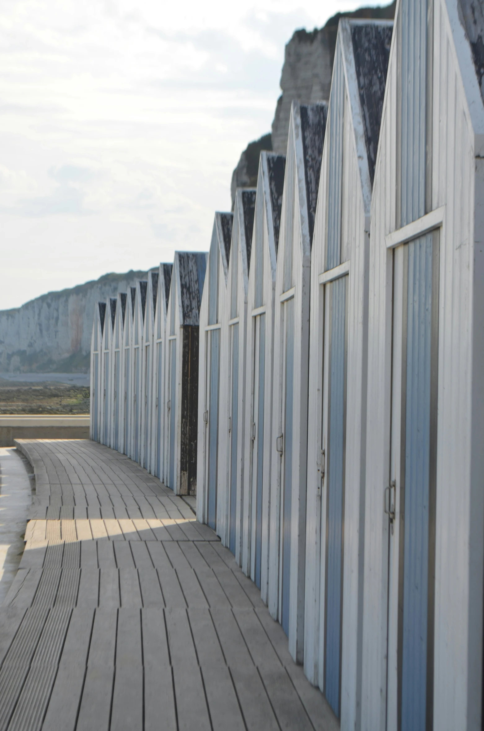 several white beach huts along a boardwalk by the water