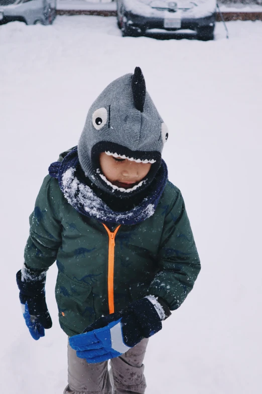 a little  standing in the snow wearing a jacket