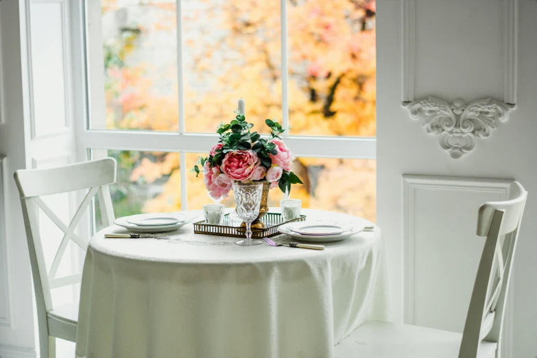 there are flowers sitting on the table, with dishes and cups