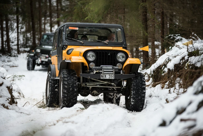 two jeeps traveling in the snow during the day