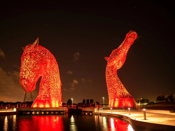 two large, intricate illuminated sculptures are sitting along a river