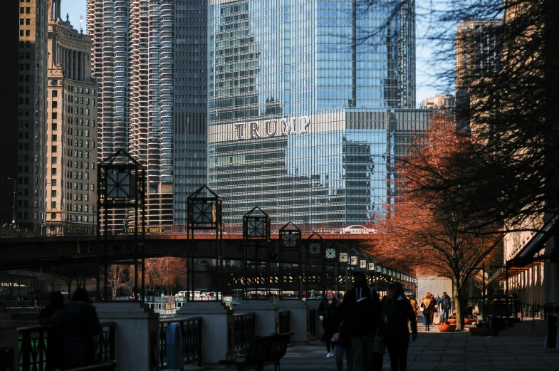 people walk down a street in front of a tall building