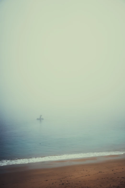 an empty beach with an orange boat floating in the water