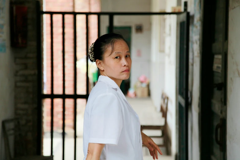 a woman in a white shirt stands outside of a prison