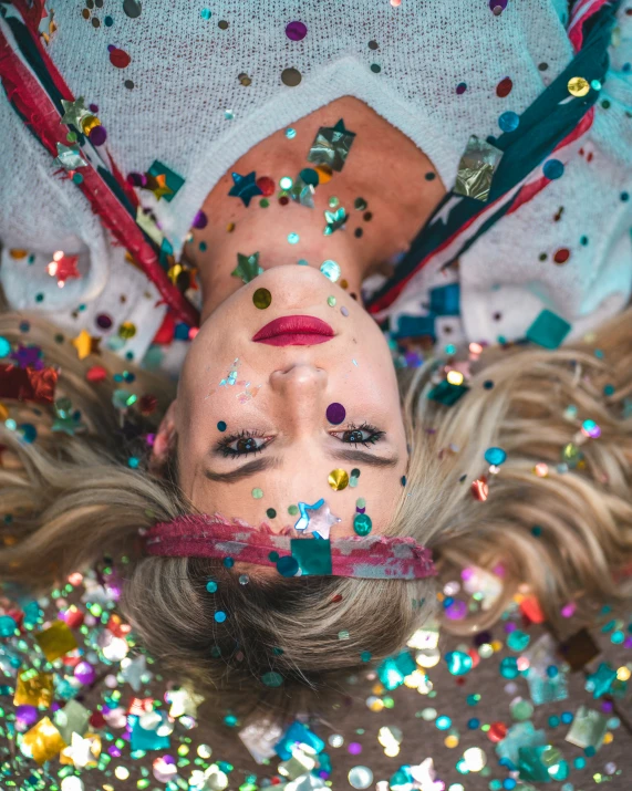 a woman laying down with lots of confetti on her face