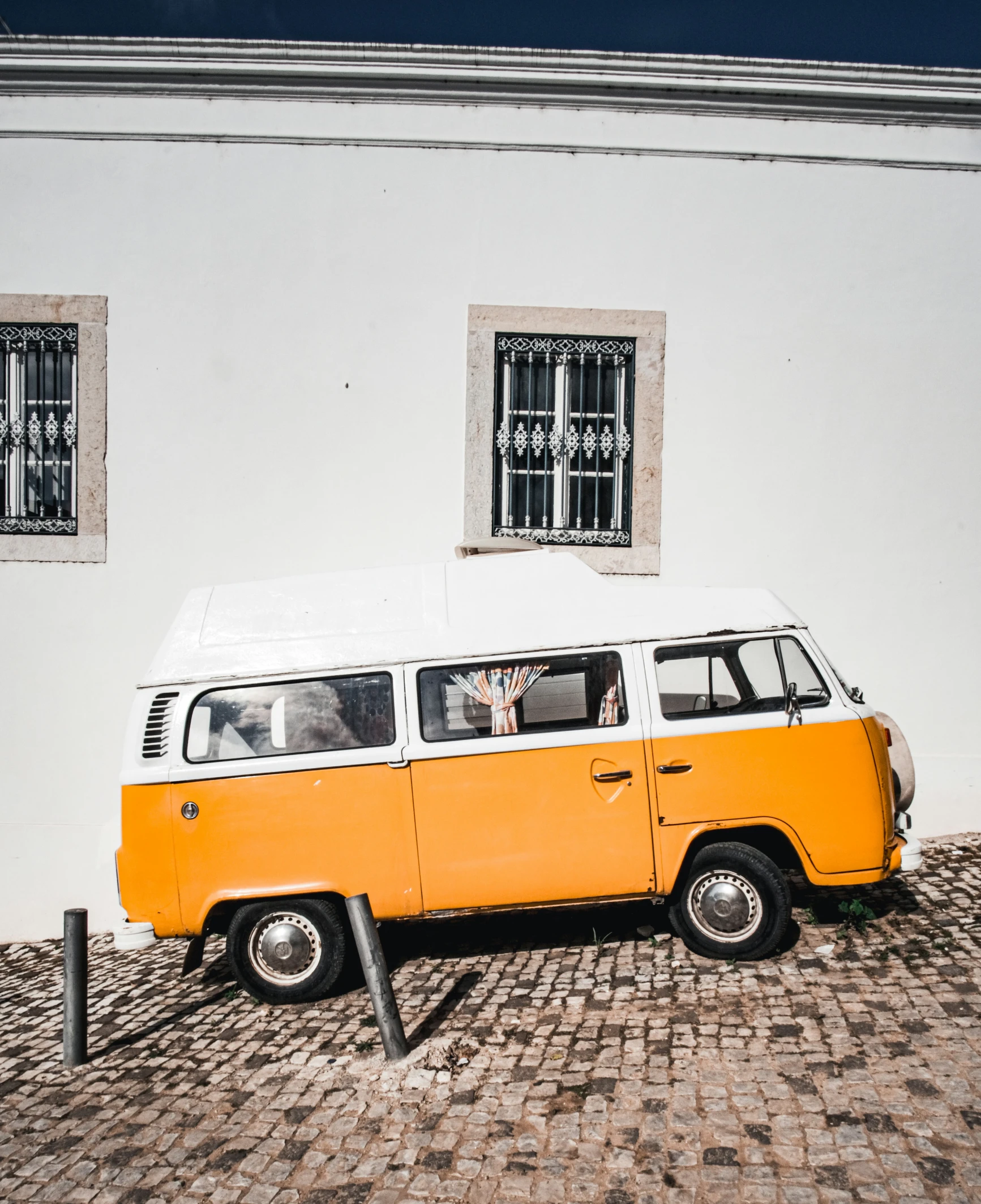 an orange and white vw bus parked on cobblestone street