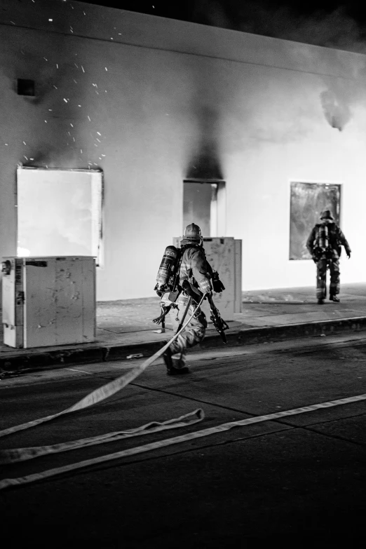 two men running through the street with fire hoses