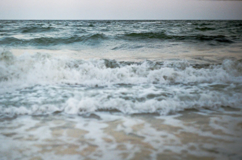 a wave is breaking into the sandy beach