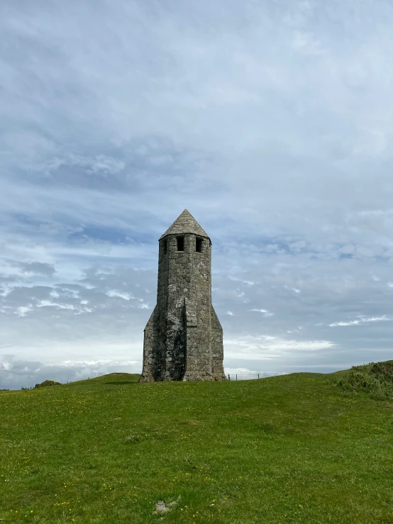 an old tower stands in a grassy field