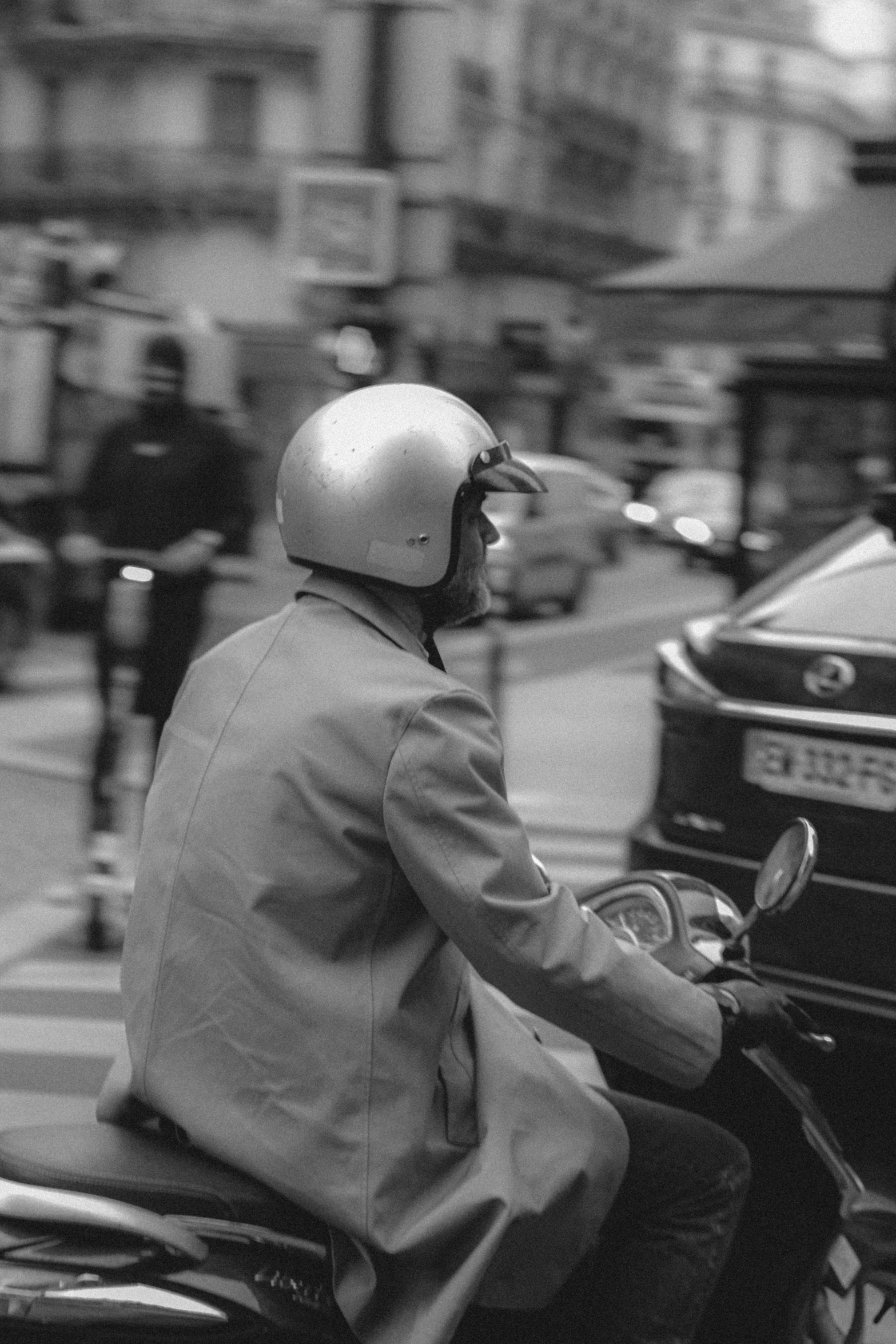 a man wearing a suit and helmet sitting on a motorcycle in front of some traffic