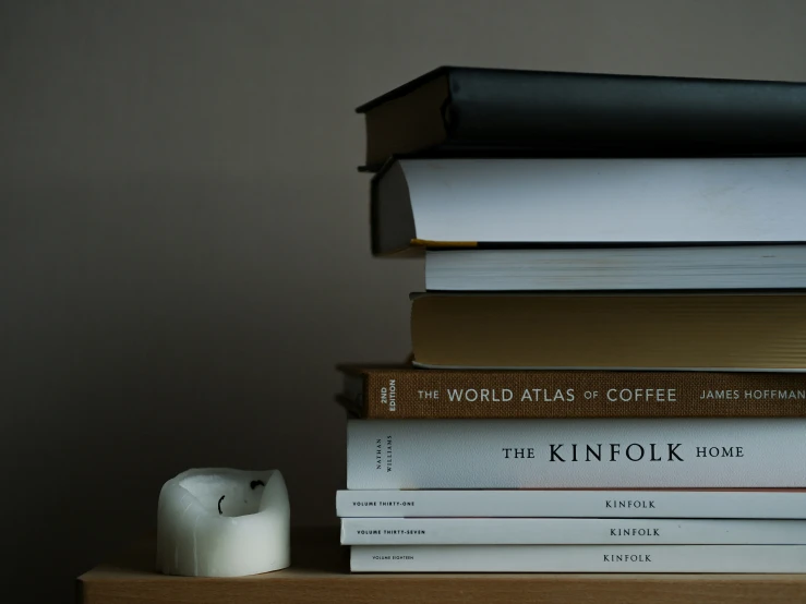 the stack of books is next to an alarm clock