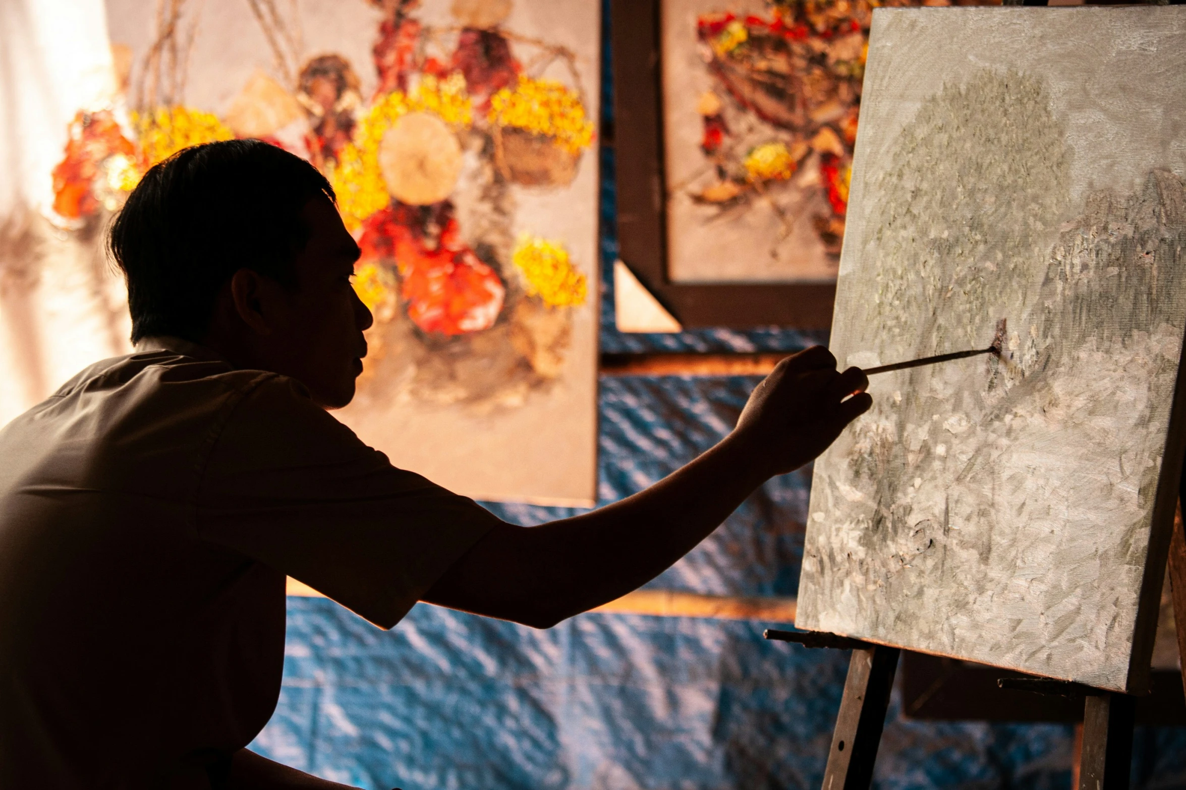 a man sitting down while painting with easel