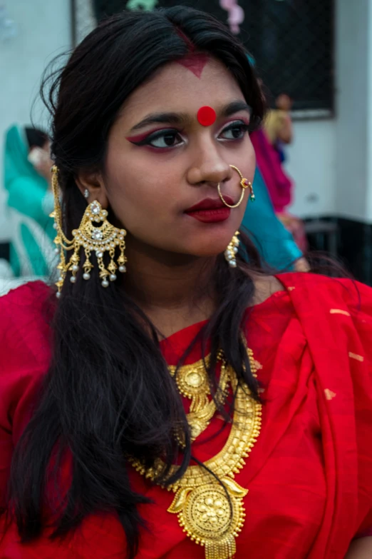 a woman wearing a red saree and earrings