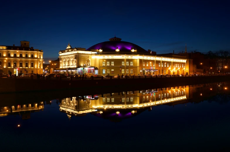 a big building by the water with lights around it