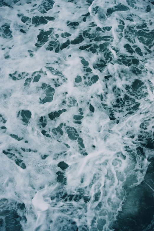 the ocean waves are crashing with rocks and bubbles