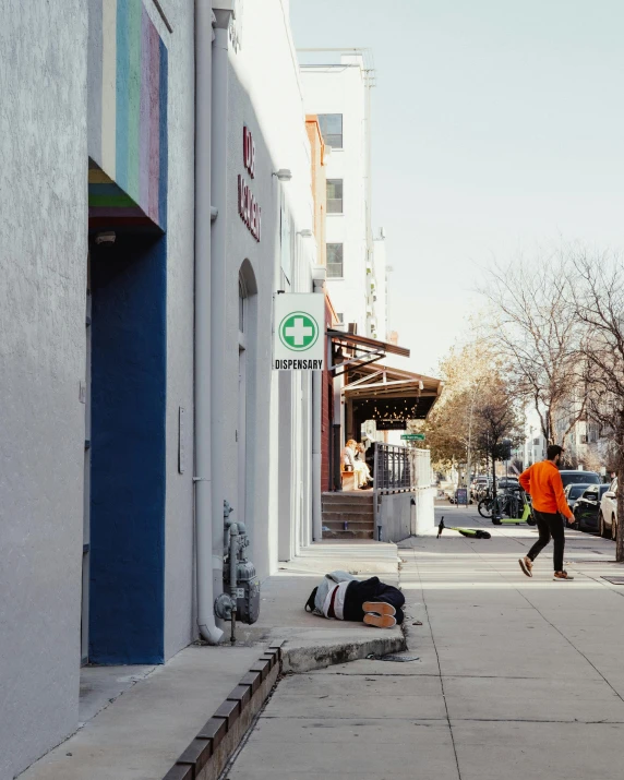 a man in an orange jacket is jumping down the sidewalk