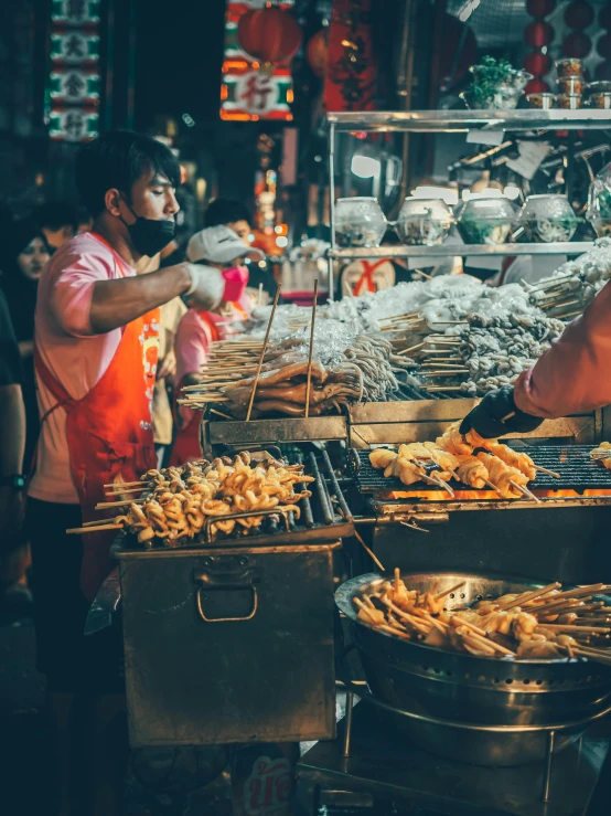 a person grilling food at a crowded street vendor