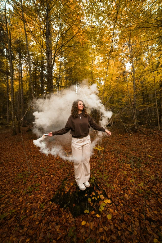 a girl throwing white smoke in the middle of the forest