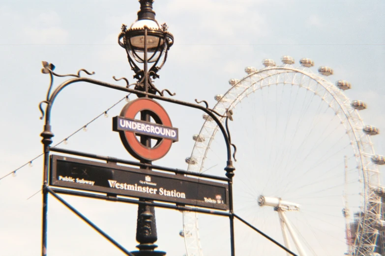 an old fashioned sign has a bright red circle on it and a large ferris wheel in the background