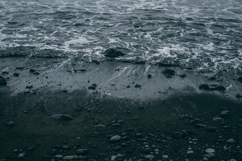 the sand is wet and there are small rocks left by the surf