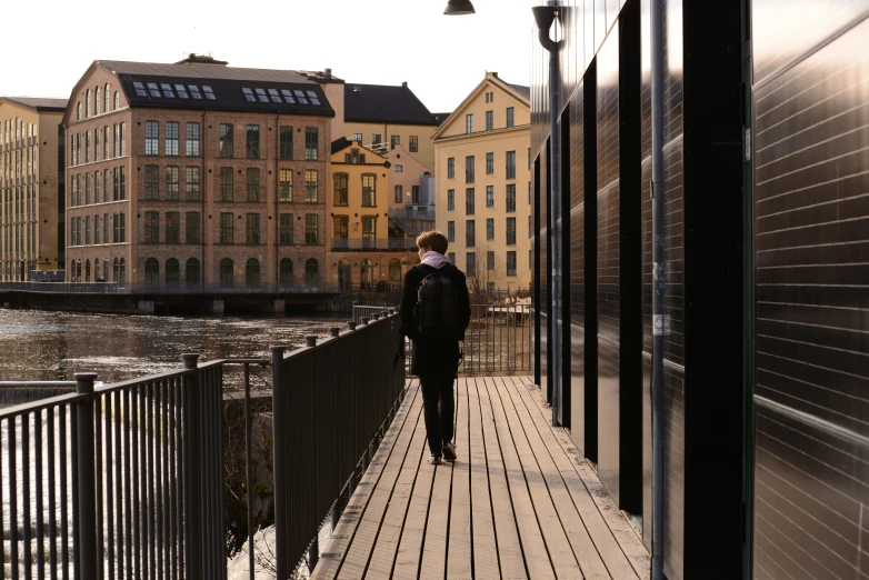 a woman walking down a bridge to some buildings