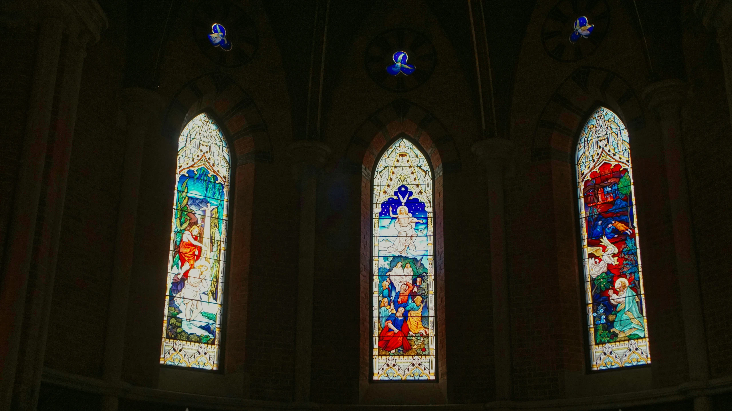 three stained glass windows with some people on them