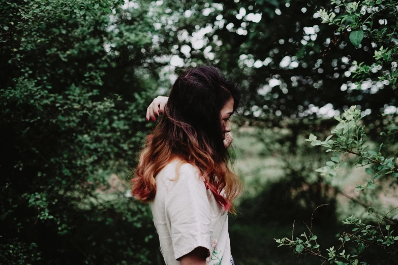 a woman in white standing in front of trees