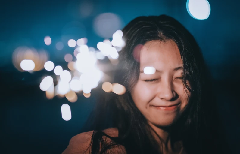 a young lady holding up a lit cellphone