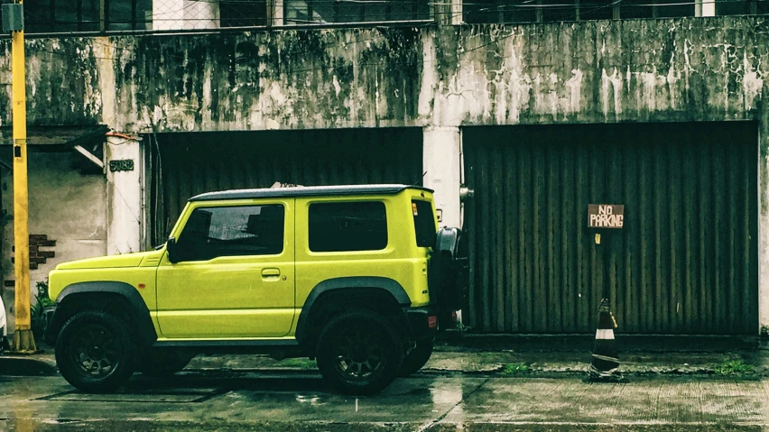 a yellow jeep is parked by a building with graffiti